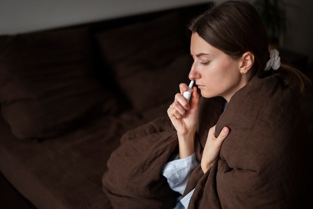 Free photo medium shot woman using nasal spray