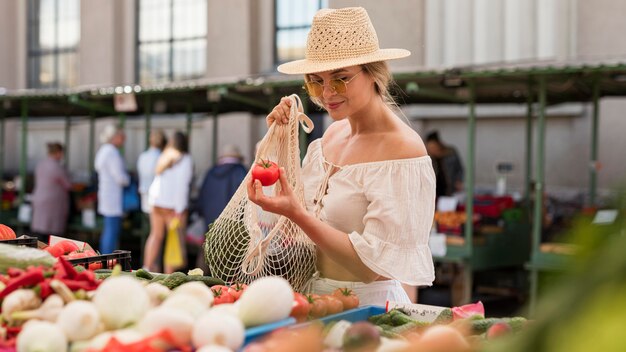 Medium shot woman using organic bag for veggies