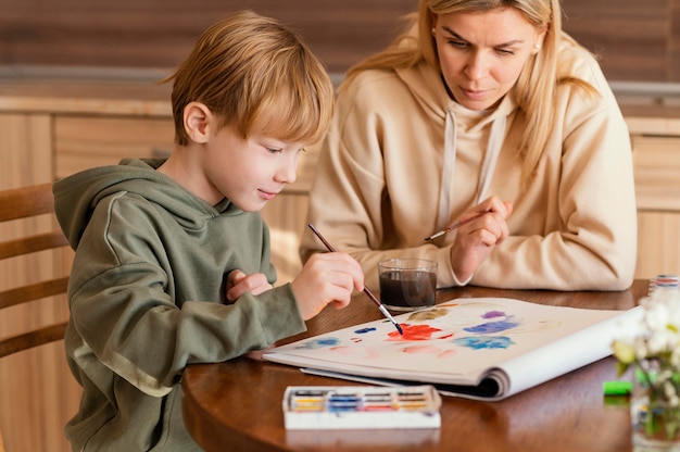 Medium shot woman watching kid paint