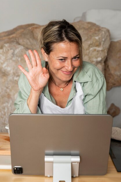 Medium shot woman waving at tablet