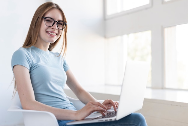 Medium shot woman with glasses working on her laptop