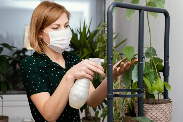 Medium shot woman with mask watering plant