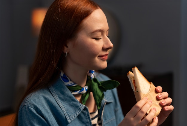 Medium shot woman with  paper-wrapped sandwich