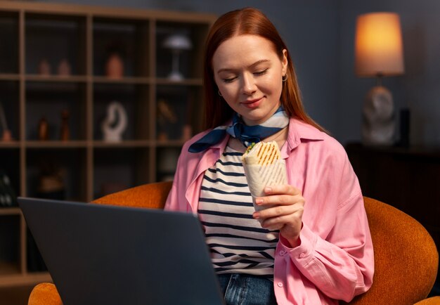 Medium shot woman with  paper-wrapped sandwich