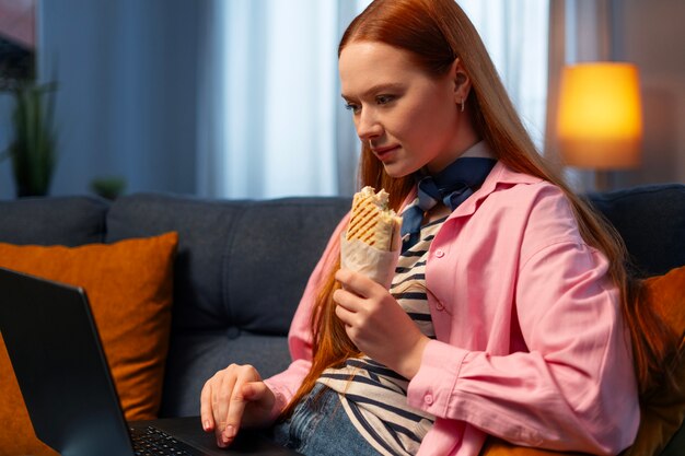 Medium shot woman with  paper-wrapped sandwich