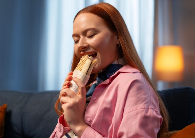 Medium shot woman with  paper-wrapped sandwich