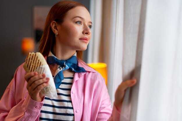 Medium shot woman with  paper-wrapped sandwich