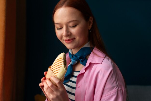 Medium shot woman with  paper-wrapped sandwich