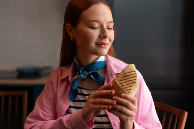 Medium shot woman with  paper-wrapped sandwich