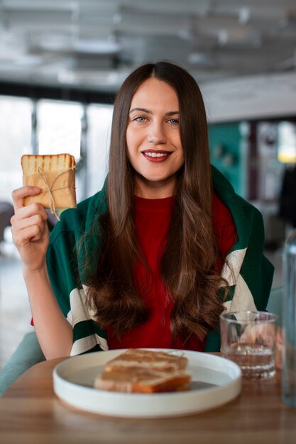 Medium shot woman with paper-wrapped sandwich