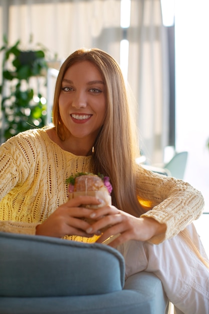 Medium shot woman with paper-wrapped sandwich