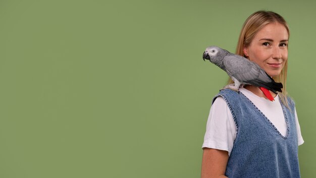 Medium shot woman with parrot in studio