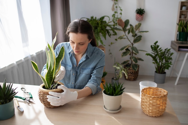 Medium shot woman with plant at home