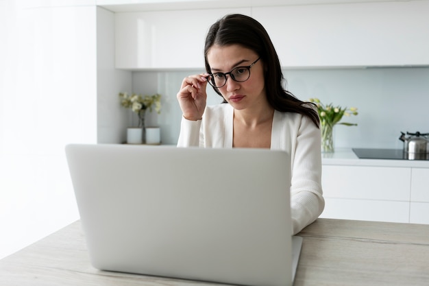 Medium shot woman working on laptop at home