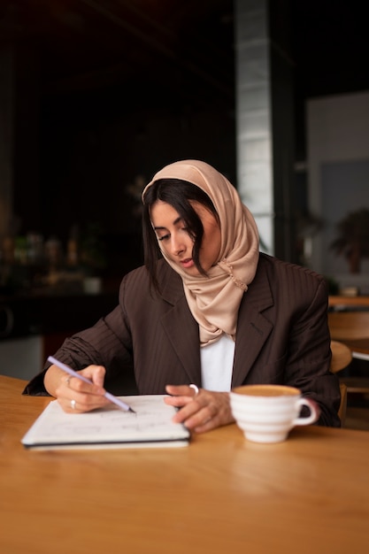 Free photo medium shot woman working with hijab indoors