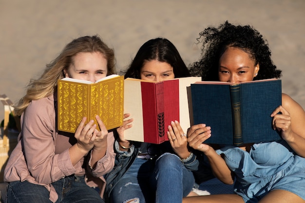 Medium shot women holding books at beach