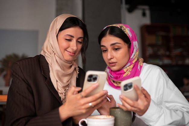 Medium shot women holding smartphones