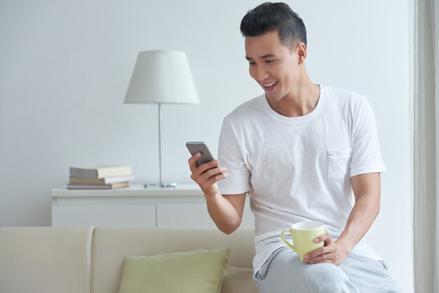 Medium shot of young gut busy texting messages in his social media on smartphone in the morning