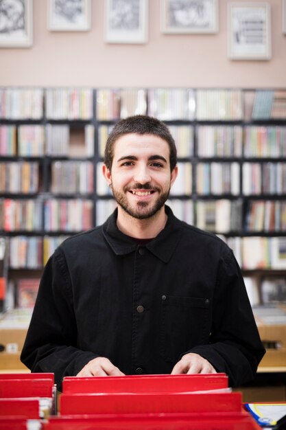 Medium shot of young man looking at camera in vinyl store