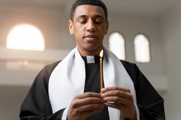 Medium shot young priest holding candle