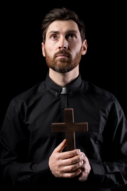 Medium shot young priest praying with cross