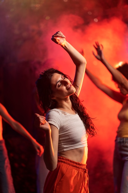 Medium shot young woman dancing at techno party