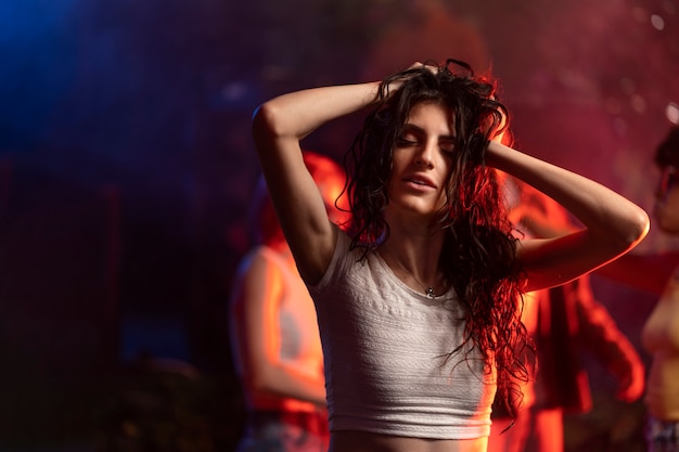 Medium shot young woman dancing at techno party