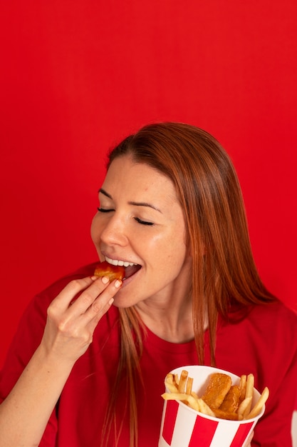 Free photo medium shot young woman eating fast food