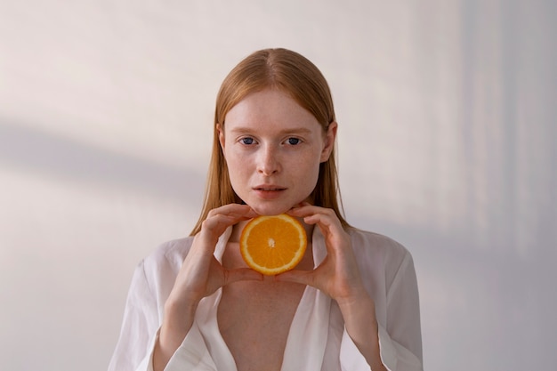 Medium shot young woman holding orange slice