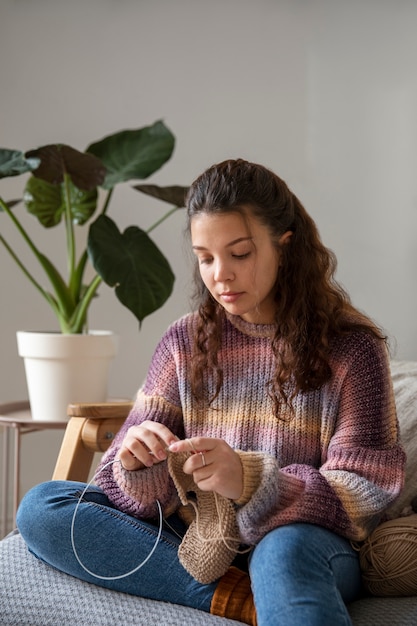 Free photo medium shot young woman knitting at home