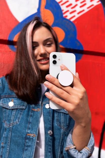 Medium shot young woman using popsocket