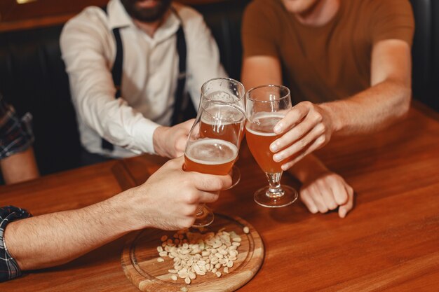 Meeting with the best friends. Three happy young men in casual wear talking and drinking beer while sitting in bar together.