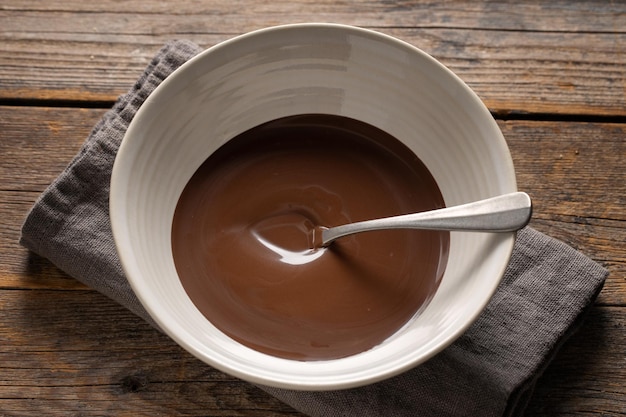 Melted chocolate in cup on grey background. Closeup