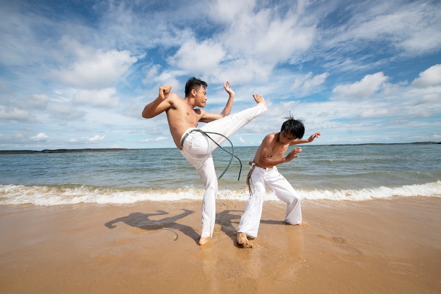 Free photo men by the beach practicing capoeira together