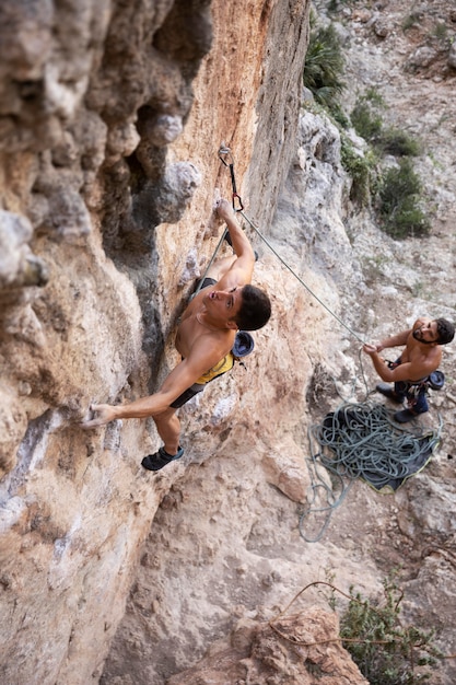 Free Photo men climbing on a mountain with safety equipment