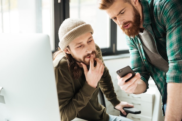 Free photo men colleagues in office using mobile phone