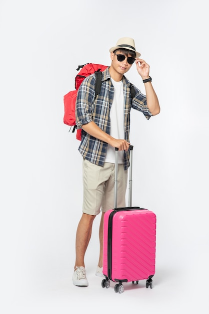 Men dressed to travel, wearing glasses and hats, carrying bags and luggage