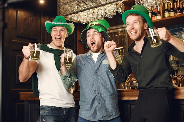 Men in green hats. Friends celebrate St. Patrick's Day. Celebration in a pub.