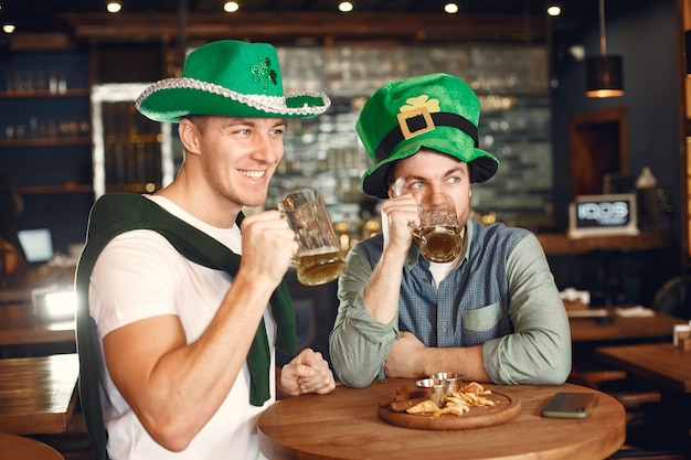 Men in green hats. Friends celebrate St. Patrick's Day. Celebration in a pub.