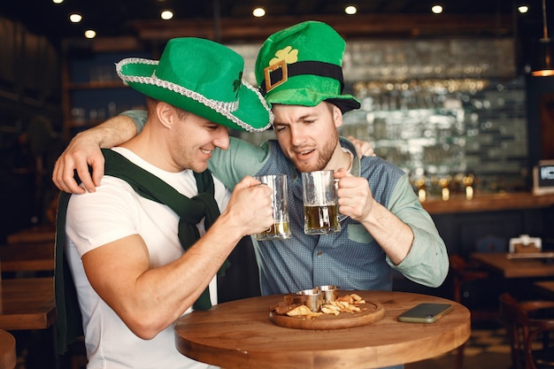 Free photo men in green hats. friends celebrate st. patrick's day. celebration in a pub.