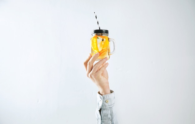 Free photo men hand presents homemade cold lemonade from oranges, sparkling water and ice cubes isolated on white.