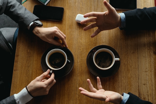 Free Photo men hands gesticulating while holding cups of coffee