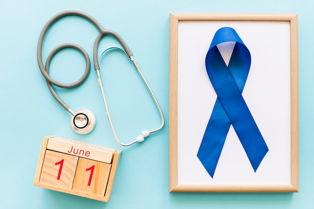 Free Photo men�s health week awareness blue ribbon on wooden white frame and stethoscope