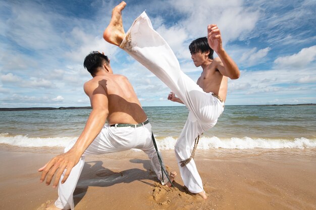 Men training for capoeira on the beach