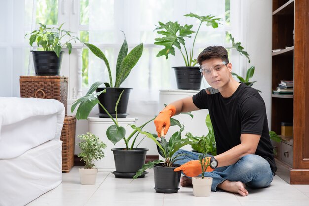 Men wearing orange gloves and planting trees indoors.