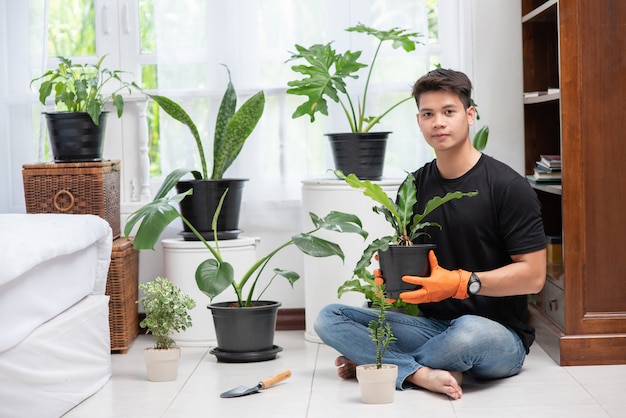 Men wearing orange gloves and planting trees indoors.