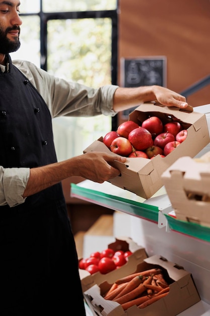 Free photo merchant carrying box of apples in store