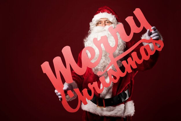 Free Photo merry christmas sign holding by santa claus