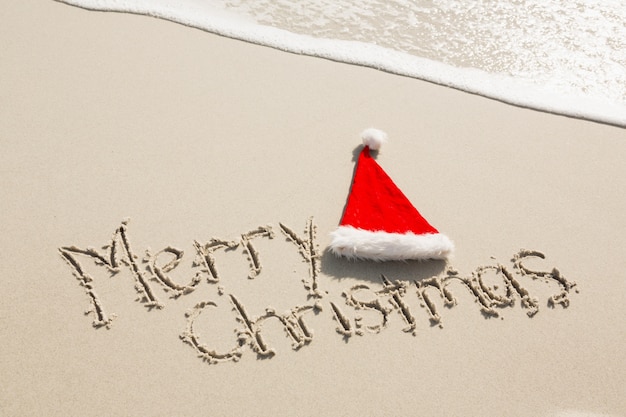 Free Photo merry christmas written on sand with santa hat