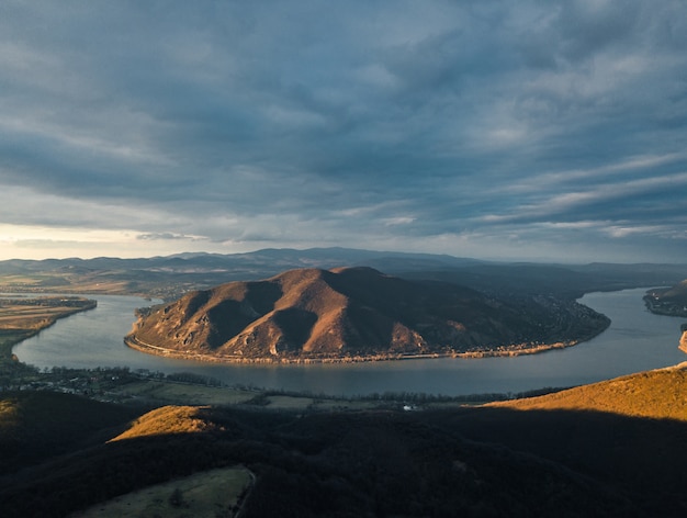 Free photo mesmerizing scene of a river between forest and hill under the cloudy sky